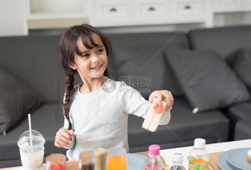 快乐的小女孩在客厅里给三明治烹饪玩具当厨师童趣与幸福教育与发展理念可爱女孩的学习和休闲托儿图片