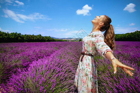 幸福的现代女人在法国普罗旺斯的薰衣草田里穿着花裙子图片