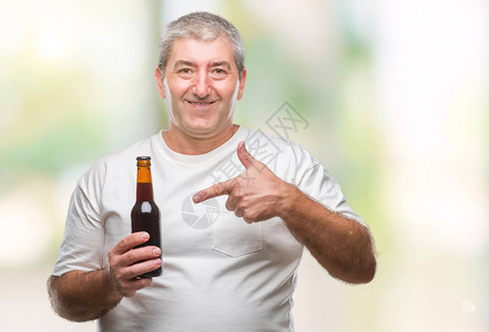 英俊的老年帅哥在孤立的背景下喝啤酒瓶非常快乐地用图片