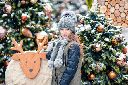 在户外的圣诞树附近的小女孩图片