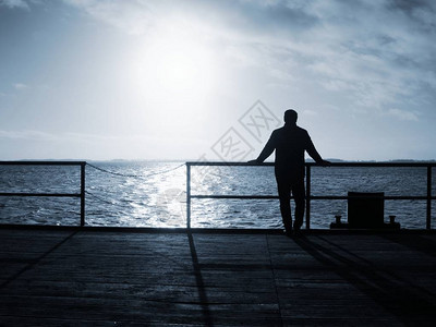 老人在码头扶手上观看早晨的大海桥上的人在Dranske镇图片