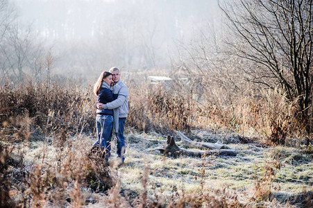 在寒冷的冬天爱和亲吻中年轻情侣在寒冬长河中的图片
