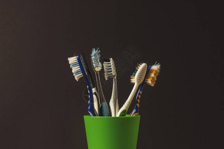 黑色背景上塑料杯中的许多牙刷更换牙刷口腔卫生牙科的概念大图片