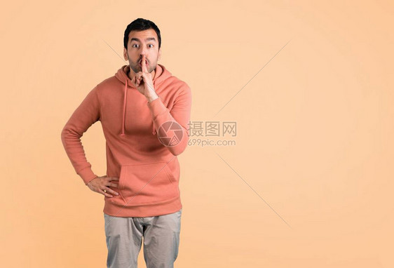 穿着粉红色运动衫的男人表现出闭上嘴和沉默的手势将手指插在嘴里在Oc图片