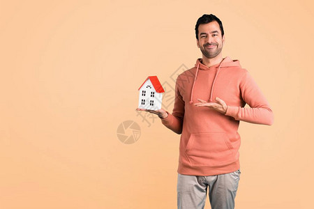 穿着粉红色运动衫的男人拿着一栋小房子在Oc图片