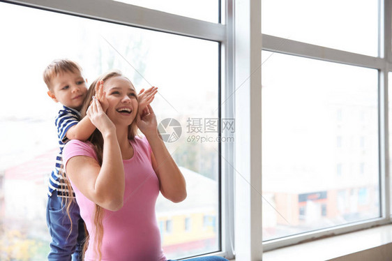 年轻孕妇在窗户旁边玩耍与可爱的图片