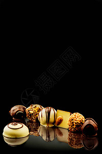 黑色镜子表面的巧克力糖果洒满椰子薯片和栗子图片