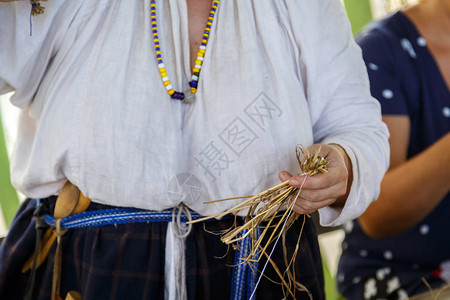 穿着传统亚麻白色衣服的俄罗斯妇女用稻草为孩子编织玩具俄罗斯图片