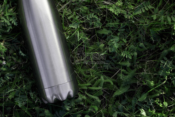 不锈钢热水瓶隔离在草背景上图片