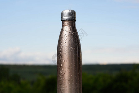 用水喷洒的无热不锈瓶本底天空和森图片