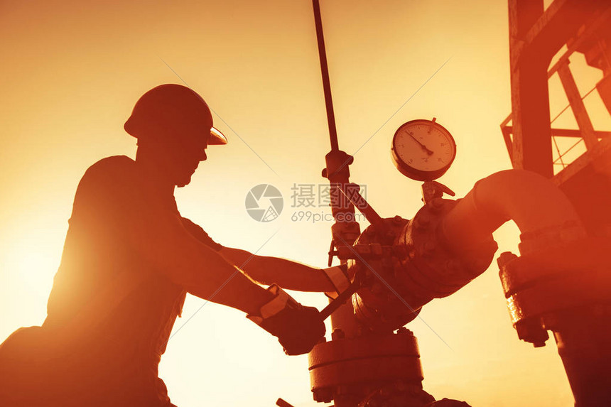 石油工人正在检查日落时的油泵以图片