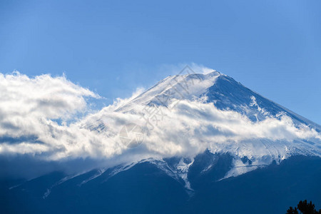 紧贴在美丽的藤山的顶端上面有雪盖白云和蓝天图片