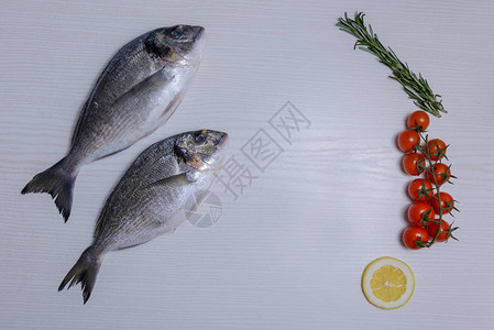 两条新鲜的多拉达鱼配有西红柿迷迭香和图片