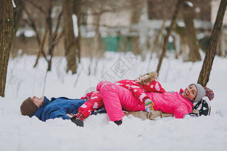 穿着冬季保暖衣服的男人小女孩躺在雪地上图片