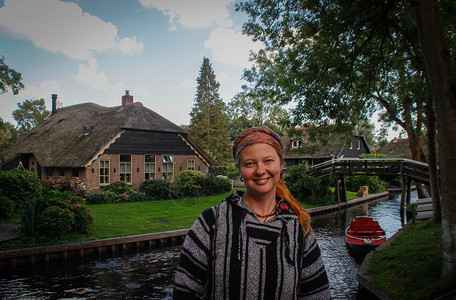 参加民族毛衣和班达纳的年轻女游客站在荷兰著名的Githorn村的背图片