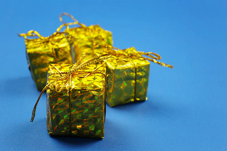 蓝纸背景和影印空间上的金礼物盒请查看InfoFin图片