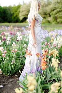 身着白衣的年轻女子站在花园的花岗岩附近图片
