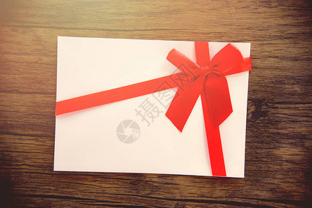 木制背景礼品卡粉红色白礼品卡装饰着红丝带蝴蝶结图片