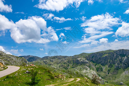 蜿蜒狭窄的道路穿过风景如画的草地和山脉图片