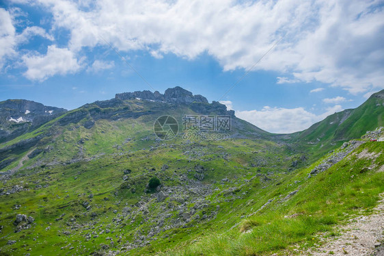 绵延在风景如画的群山之间的绿色草地图片