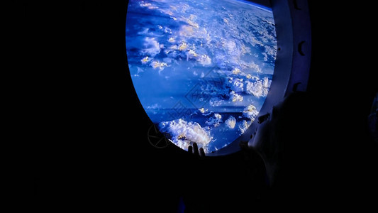 一个美丽的女人望着国际空间站舷窗的大圆窗图片