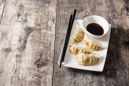 木桌上的饺子或饺子和酱油复制空间图片