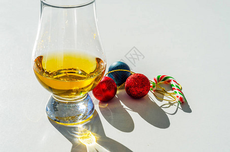 配有糖果甘蔗和圣诞球的单一麦威士忌杯图片
