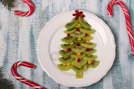 由猕猴桃玉米和石榴制成的圣诞树圣诞节和节日菜肴的创意图片