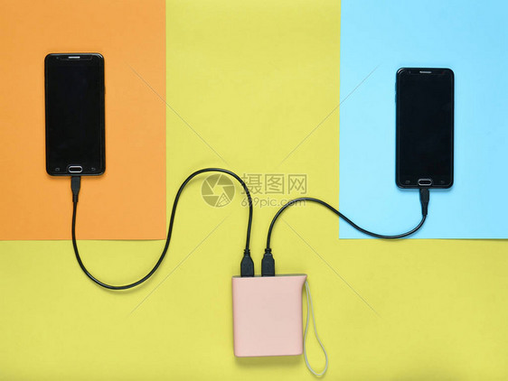 电动银行以彩色糊面背景向两台智能手机收费现代工具顶图片