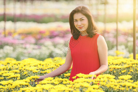 穿着红色连衣裙的可爱亚洲女人站在花丛中图片