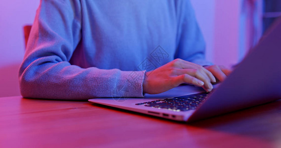女人在带紫色光的笔记本电脑上工作图片