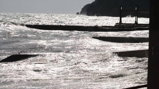 海浪和码头在日落与太阳光线图片