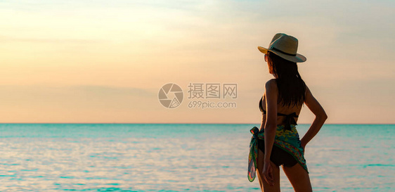 身穿黑色泳衣和草帽的快乐亚洲年轻女背影在日落时分在热带天堂海滩放松和享受假期暑假时尚的女孩美女感模特优图片