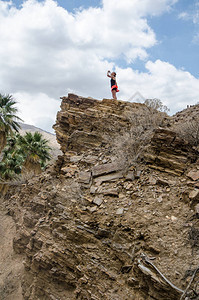 在棕榈泉峡谷的悬崖上站着一个适合运动的女徒步旅行者图片