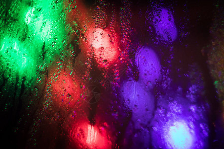 夜间城市的灯光穿过湿玻璃图片