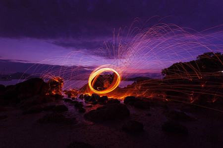 摆动火漩涡钢丝绒光摄影在石头上反射在水中日出或日落时的美丽光线图片