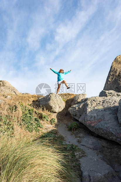 女在俄勒冈海岸上从一块大岩石上跳下关于信仰兴奋勇敢自信图片