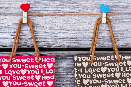 装有浪漫模式的纸袋挂在绳子上的固定礼品袋和心形衣物情人节礼物包图片