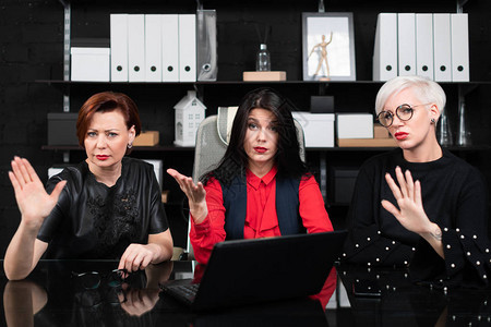 在电脑桌前工作的企业家三名女商人在现代办公室使用笔记本电脑开会图片
