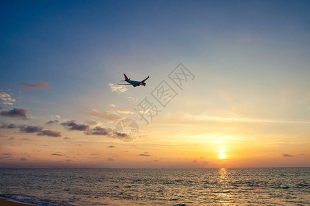 飞机在日落时在海面上飞行图片