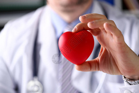 男医学生在他的胸部特写前抱着红色的玩具心脏治疗师学生教育心肺复苏术救生医师做心脏物理心率图片