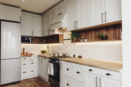 灰色的豪华现代厨房家具和钢烤箱冰箱水槽木桌面锅斯堪的纳维亚风格的灰色橱柜家居装修时尚的背景图片