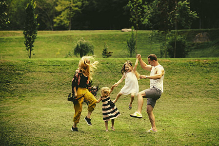 自由活动生活方式能源概念母亲节和父亲节孩子们和家长们在绿草地上跳跃快乐的童年背景图片