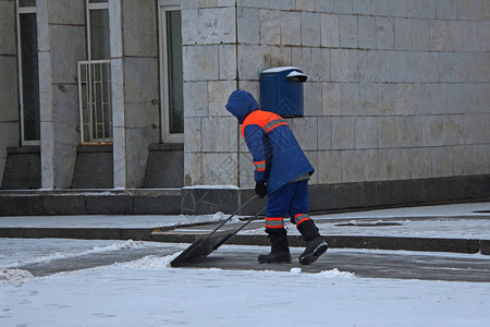 用铲子在人行道上擦雪的J图片