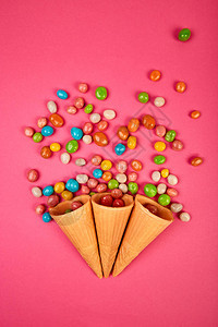 冰淇淋华夫饼锥与五颜六色的糖果糖果冻散落在粉红色背景上的五彩糖果图片
