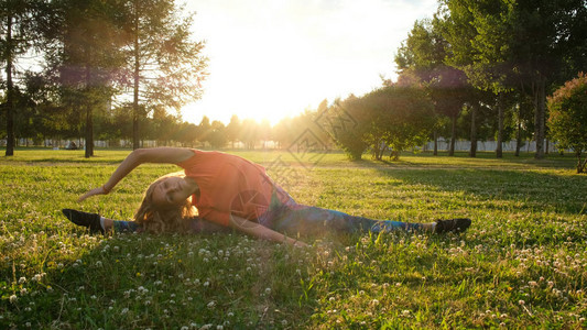 女体操运动员坐在自然中的城市公园的草地上坐着一根绳子图片