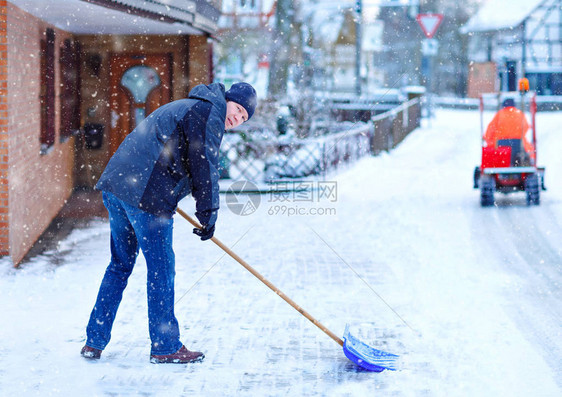 有雪铲的人在降雪期间在冬天清理人行道欧洲的冬天穿着温暖冬衣的年轻人德国的雪和天气混乱暴风雪和大图片