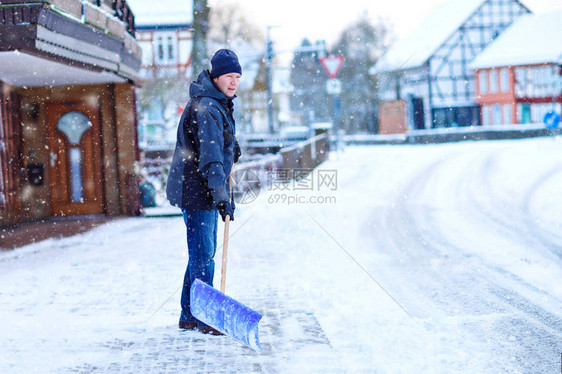 有雪铲的人在降雪期间在冬天清理人行道欧洲的冬天穿着温暖冬衣的年轻人德国的雪和天气混乱暴风雪和大图片