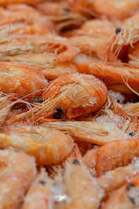 宏观照片新鲜解冻的美味虾与扭曲的尾巴特写一个柜台的宏观照片与新鲜冷冻的橙色虾海冻虾在白霜中的图片