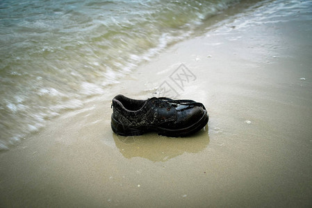 鞋子垃圾海滩海水污染海滩沙子上的旧鞋图片